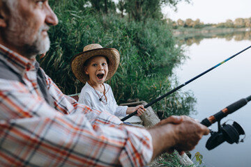 boy fishing on the lake with his grandfather