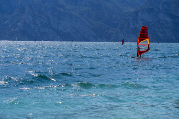 Surfer catching the wind on the stormy lake of Garda with the mountains in the background