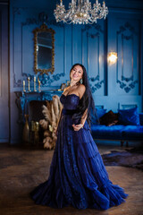 Beautiful woman in a blue ball gown and blue room
