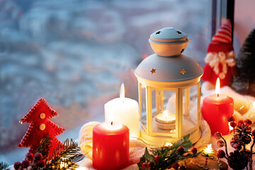 Winter Christmas holidays background with candles; christmas light; Cup of cocoa with marshmallow or hot chocolate near a window