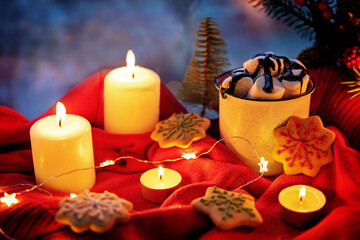 Winter Christmas holidays background with candles; christmas light; Cup of cocoa with marshmallow or hot chocolate near a window