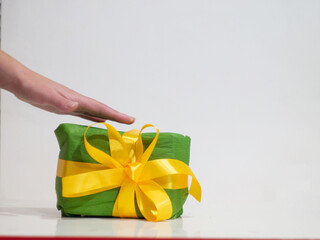 woman giving a green box with yellow bow as a gift