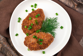Fish cutlets with fresh herbs on a brown wooden background. The view from the top. The concept of cooking.