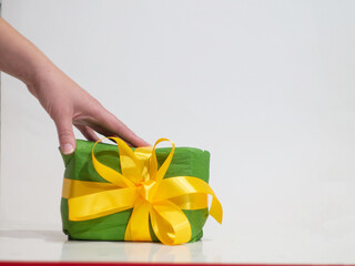woman giving a green box with yellow bow as a gift