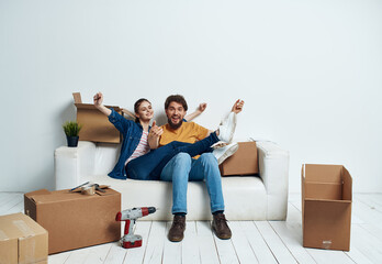 Fototapeta na wymiar Young couple with things in boxes on the couch moving housewarming interior