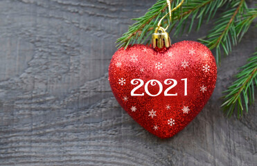 2021 New Year greeting card with red Christmas heart and fir tree branch on old wooden background.Winter holidays festive decoration with copy space.