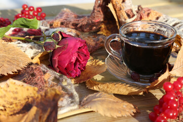 Autumn still life with a rose, a cup of coffee and a warm knitted scarf