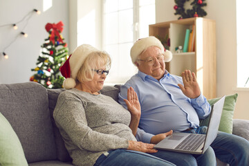 Obraz premium Senior couple using laptop makes a video call to congratulate their family on Christmas.