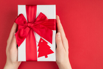 Christmas shaping presents concept. Pov top above overhead close up view photo of female hands holding gently large gift box with label in shape of fir tree isolated background with empty blank space