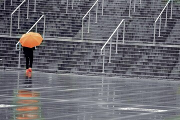 Dziewczyna w deszczu z pomarańczowym parasolem