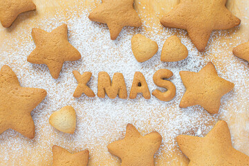 Christmas food. Cookies in the form of XMAS lettering in the form of gingerbread cookies stars on the background of a rolling board with powdered sugar. 