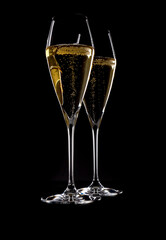 Two Elegant Crystal Champagne Flutes Filled with Sparkling White Wine Isolated on Black Background