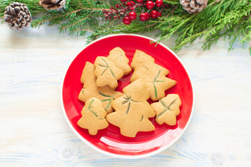 Christmas food. Organic Christmas cookies in the form of Christmas trees. Instruction step by step 4. Baked cookies on a red plate on a wooden white background and decorations around. Homemade food.