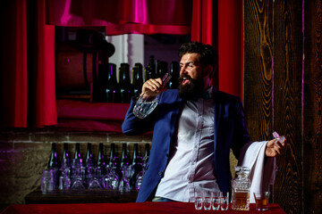 Portrait of cheerful barman worker standing. Bar man in bar interior making alcohol beverage.