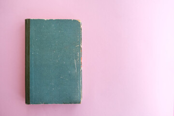 Old book of green color on a pink background.
