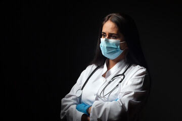 Female doctor wearing a disposable protective mask against covid-19 coronavirus infections on a black background