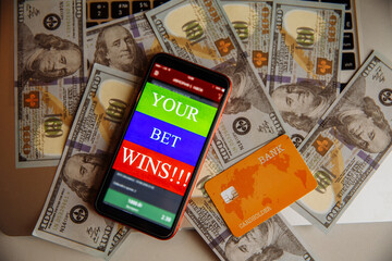 Smartphone with gambling mobile application and credit card on dollar banknotes.