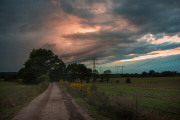 Fototapeta na wymiar Ciemne chmury nad polną drogą.