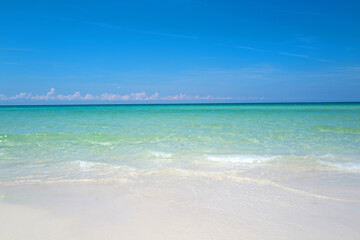 Soft blue ocean wave on clean sandy beach. Beautiful beach with blue sea water. Lagoon and white sandy beach.
