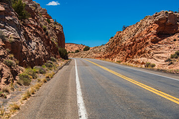 Landscape with orange rocks, sky with clouds and asphalt road in summer.