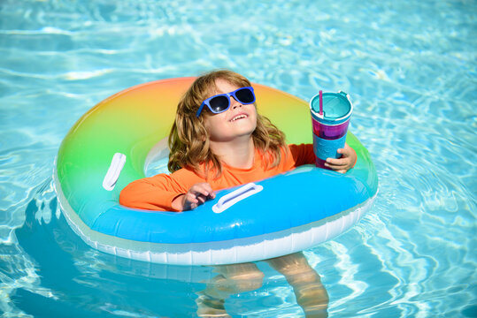 Child Swimming In Swimming Pool With Flotation Ring On Summer.