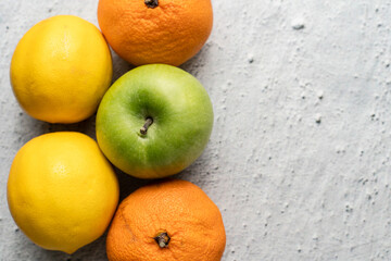 Top view on green apple granny smith with oranges and lemon on marble table - healthy organic eating fresh food rich in vitamins copy space