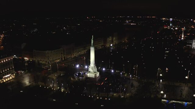 Monument of freedom at night in Riga, Latvia during Staro Riga event. Milda - Statue of liberty holding three stars over the city illuminated in different colors. 