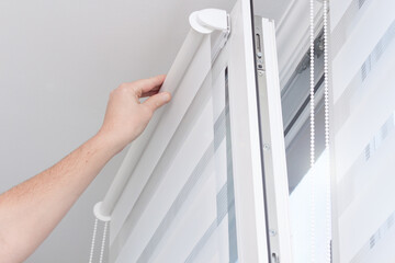 Man hands installing window roller duo system day and night.
