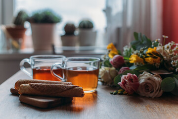 Still life. Table with mugs of tea, cookies and flowers