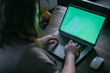 Woman working on a laptop at home, close-up of a laptop on the table and hands
