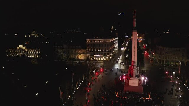 Monument of freedom at night in Riga, Latvia during Staro Riga event. Milda - Statue of liberty holding three stars over the city illuminated in different colors. 