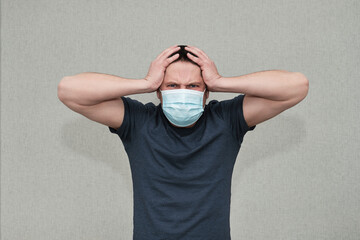 Adult White Man in surgical mask  worried, stressed and he holding his head with hands. Take Care of psychic health. People negative emotions. Tired of coronavirus pandemic. 