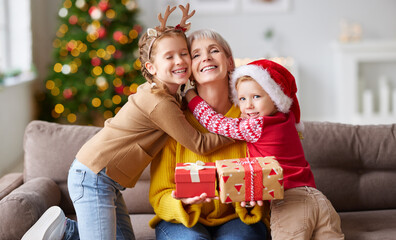 Amazed woman getting Christmas present from grandchildren.