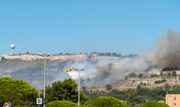 fire starts on the hills of Marseille, near Marignane airport. yellow fire-fighting plane is throwing water on it. 