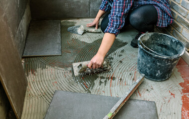 Female mason laying a new tile floor on a terrace