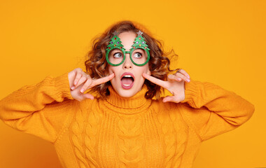 funny cheerful woman in silly glasses with Christmas trees on a yellow background