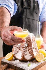 Man holds a glass of limoncello in his hands, and a soft star-shaped pasta sprinkled with icing...