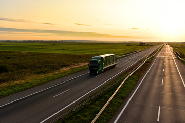 Obraz na płótnie Canvas Truck with semi-trailer driving along highway on the sunset background. Out of focus, possible granularity, motion blur