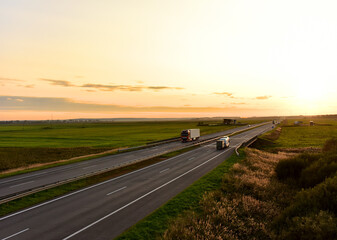 Truck with semi-trailer driving along highway on the sunset background. Out of focus, possible granularity, motion blur