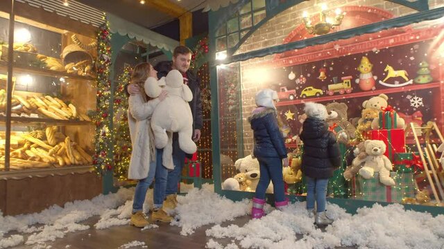 Couple walking past children near toy store and bakery