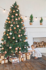 Baby on sofa near christmas tree is smiles so that two teeth are visible