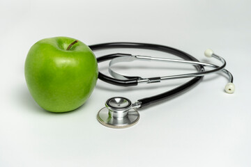 GREEN APPLE AND STETHOSCOPE ISOLATED ON WHITE BACKGROUND. HEALTH CARE, WELLNESS AND HEALTHY...