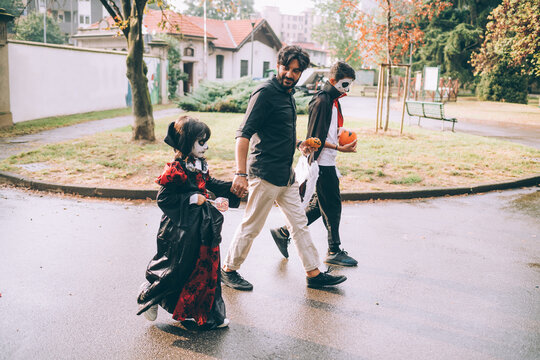 Father and children walking in Halloween costumes