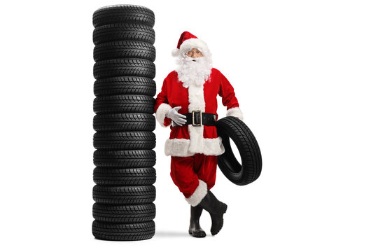 Full length portrait of santa claus leaning on a pile of tires and holding one tire