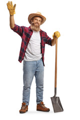 Full length portrait of a bearded farmer with a shovel waving at camera