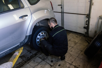 Mechanic changing car wheel in auto service workshop