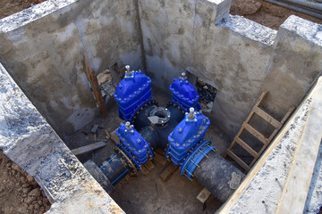 Gate valves in valve pit of the underground piping networks. Laying water system pipeline at...