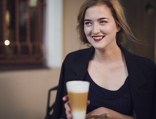 Happy woman in black dress drink coffee in a cafe
