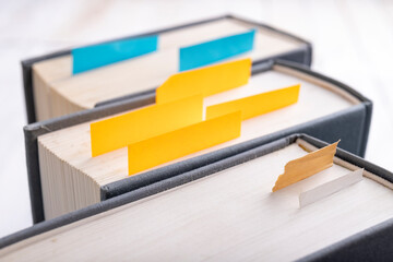 Books with colored sticky notes for marking pages. Literature in the library.