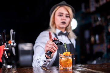 Girl bartender mixes a cocktail in the bar